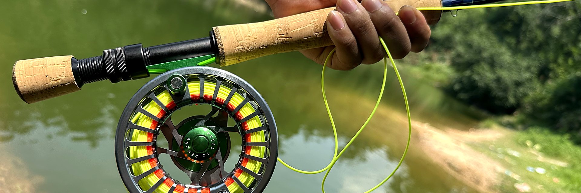 KATYUSHA fly reel with a chartreuse fly line over calm green water